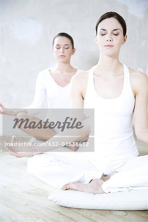 Deux jeunes femmes, assis en position du lotus, les yeux fermés