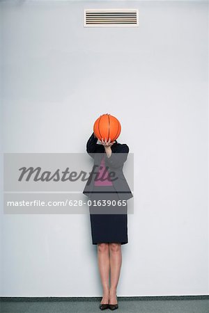 Geschäftsfrau covering Face mit einem basketball