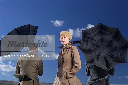 Three businesspeople in storm, businessmen under umbrellas
