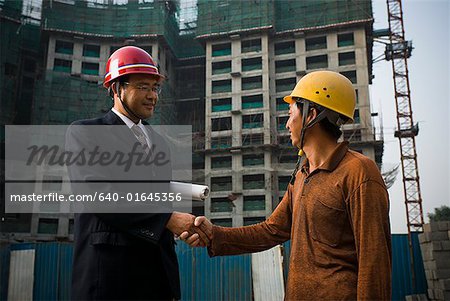 Construction foreman and worker outdoors shaking hands