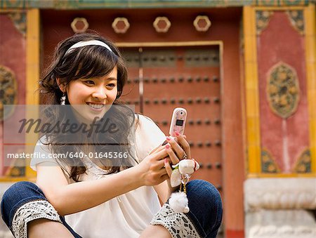 Adolescente, assis à l'extérieur avec téléphone portable