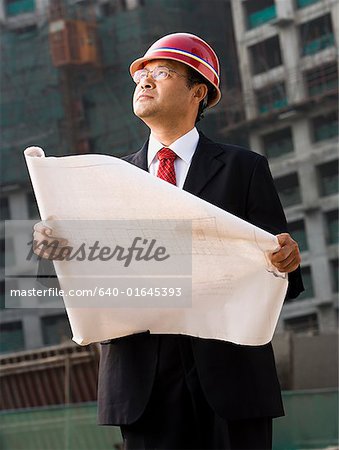 Construction site foreman with blueprints outdoors