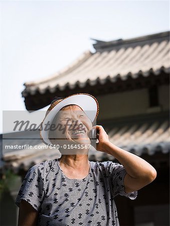 Woman with sun visor outdoors smiling talking on cell phone