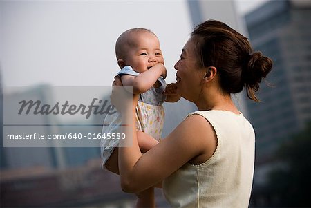 Frau hält Baby lächelnd im freien