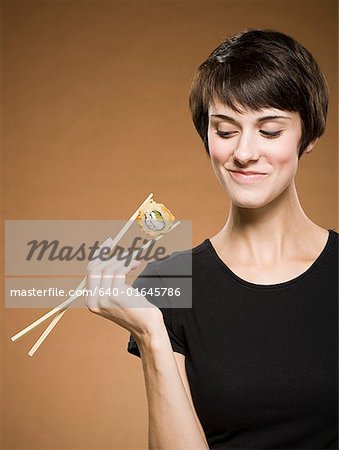 Woman holding sushi with chopsticks smiling