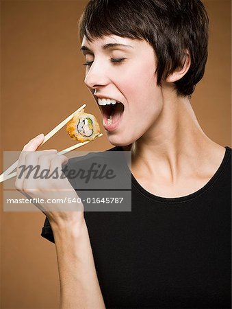 Woman holding sushi with chopsticks smiling