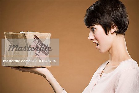 Woman holding crushed cardboard box with fragile label