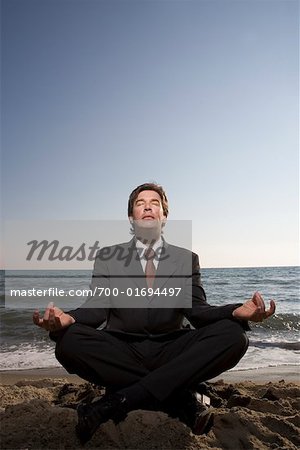 Businessman Meditating on Beach