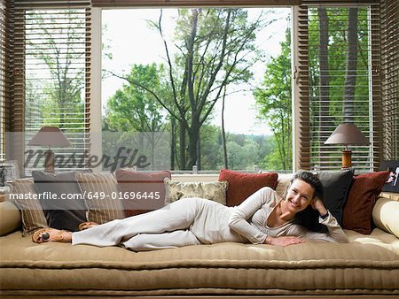 Woman lying on couch in living room smiling.