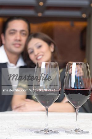 Close-up of two glasses of wine on a table in front of a couple