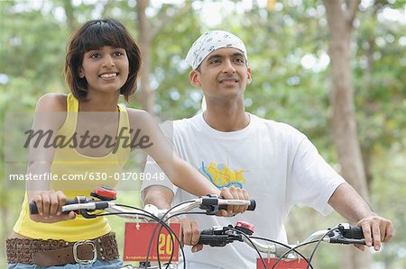 Close-up of a young couple sitting on bicycles and smiling