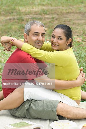 Portrait of a mid adult couple sitting in a park and embracing each other