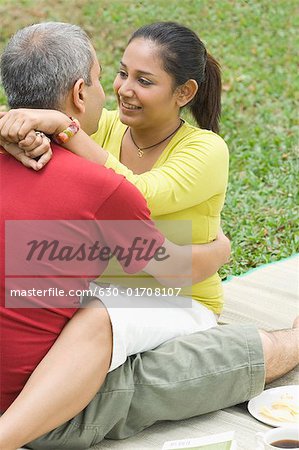 Mid adult couple sitting in a park and embracing each other