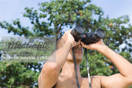 Close-up of a young man looking through binoculars