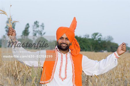 Portrait d'un jeune homme debout dans un champ de blé et la tenue des cultures