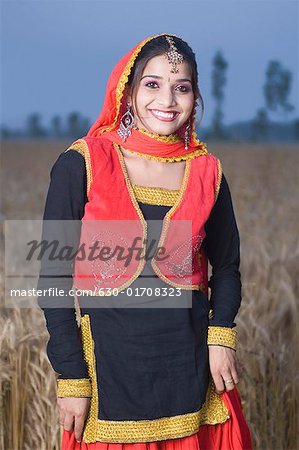 Portrait d'une jeune femme debout dans un champ de blé et souriant