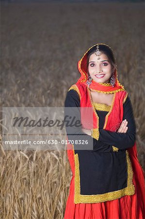 Portrait d'une jeune femme debout dans un champ de blé et souriant
