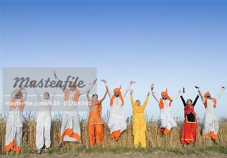 Four young couples jumping with their arms raised