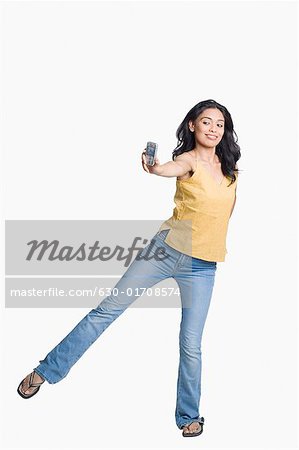 Junge Frau auf einem Bein stehen und Fotografieren des selbst mit einem Mobiltelefon