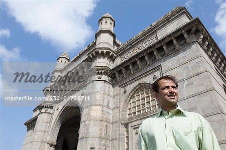 Flachwinkelansicht eines Kaufmanns steht vor einem Denkmal, das Gateway of India, Mumbai, Maharashtra, Indien