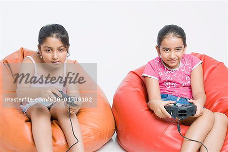Two girls sitting on bean bags and playing a video game