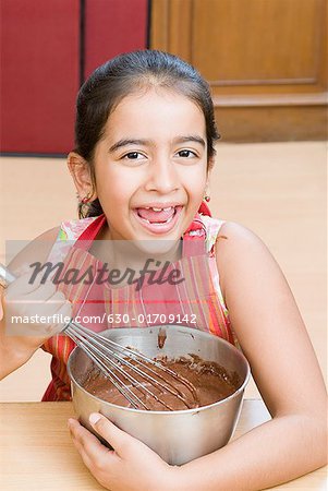 Portrait d'une jeune fille en remuant la sauce au chocolat avec un batteur à oeufs