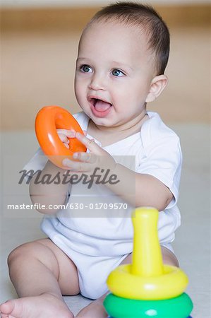 Close-up of a baby boy playing with stacking rings and smiling