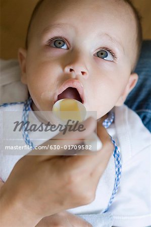 Close-up of a person's hand feeding food to a baby boy