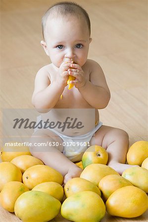 Portrait of a baby boy eating a mango