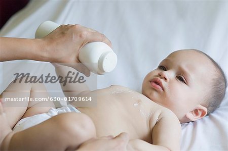 Gros plan de la main d'une personne mettant la poudre de talc sur la poitrine d'un bébé