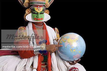 Portrait d'un artiste de danse Kathakali tenant un globe