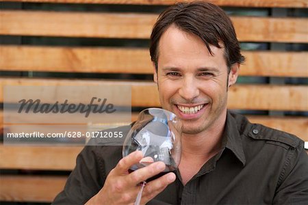 Man holding a glass of red wine while smiling at camera