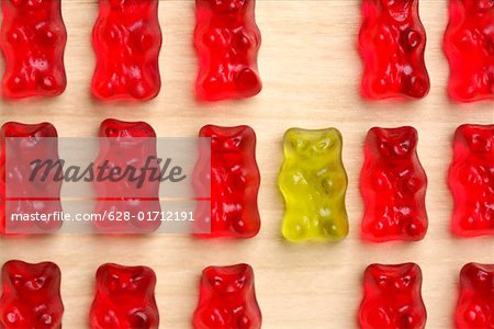 A yellow gummy bear between red gummy bears