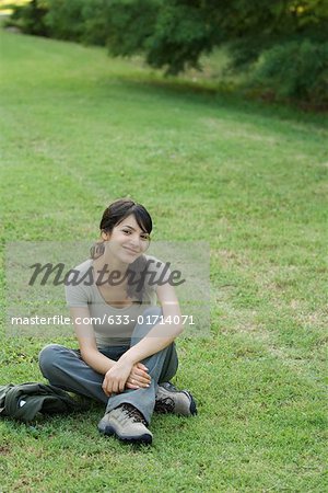 Junge Frau sitzend auf Gras, lächelnd in die Kamera