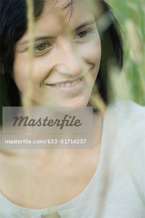 Jeune femme souriante, regardant de loin, portrait