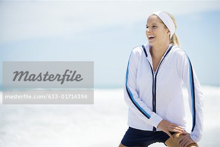 Junge Frau im aktiven Verschleiß am Strand, stretching und lachen