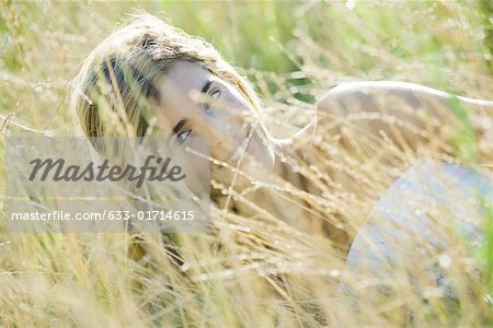 Young woman reclining in tall grass, smiling