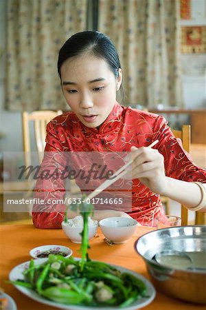 Jeune femme portant des vêtements traditionnels chinois, manger avec des baguettes