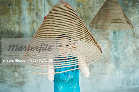 Jeune femme portant des vêtements traditionnels chinois, regardant à travers la spirale d'encens
