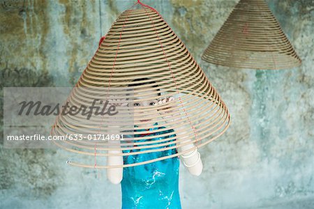 Young woman wearing traditional Chinese clothing, looking through spiral of incense