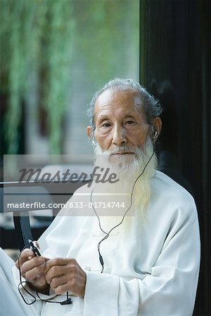Elderly man wearing traditional Chinese clothing, using MP3 player