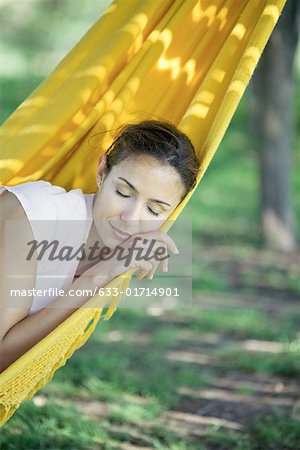 Woman resting in hammock, eyes closed