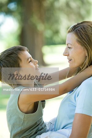 Mother holding son in arms, both smiling at each other, side view