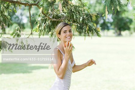 Junge Frau im Freien stehen, halten Apfel unter Kinn