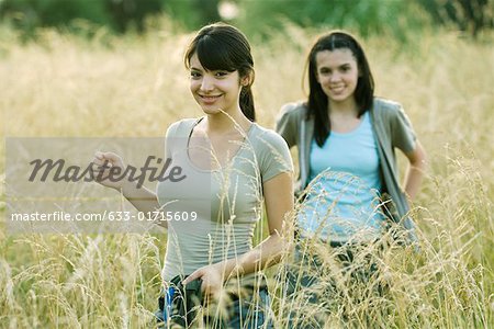 Young female hikers walking through field