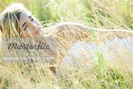 Young woman lying in field, relaxing