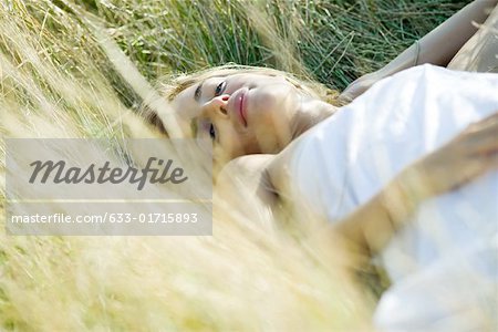 Young woman sleeping in grass, cropped view