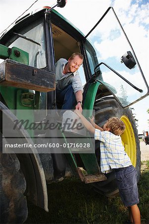 Boy Giving Lunchbox to Father in Tractor