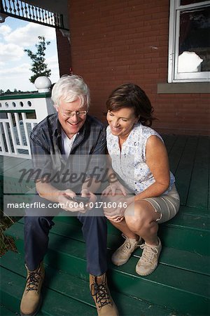 Couple with Electronic Organizer on Porch of Farmhouse