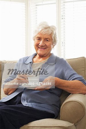 Porträt des leitenden Frau sitzt auf Sofa Holding Tasse und Untertasse